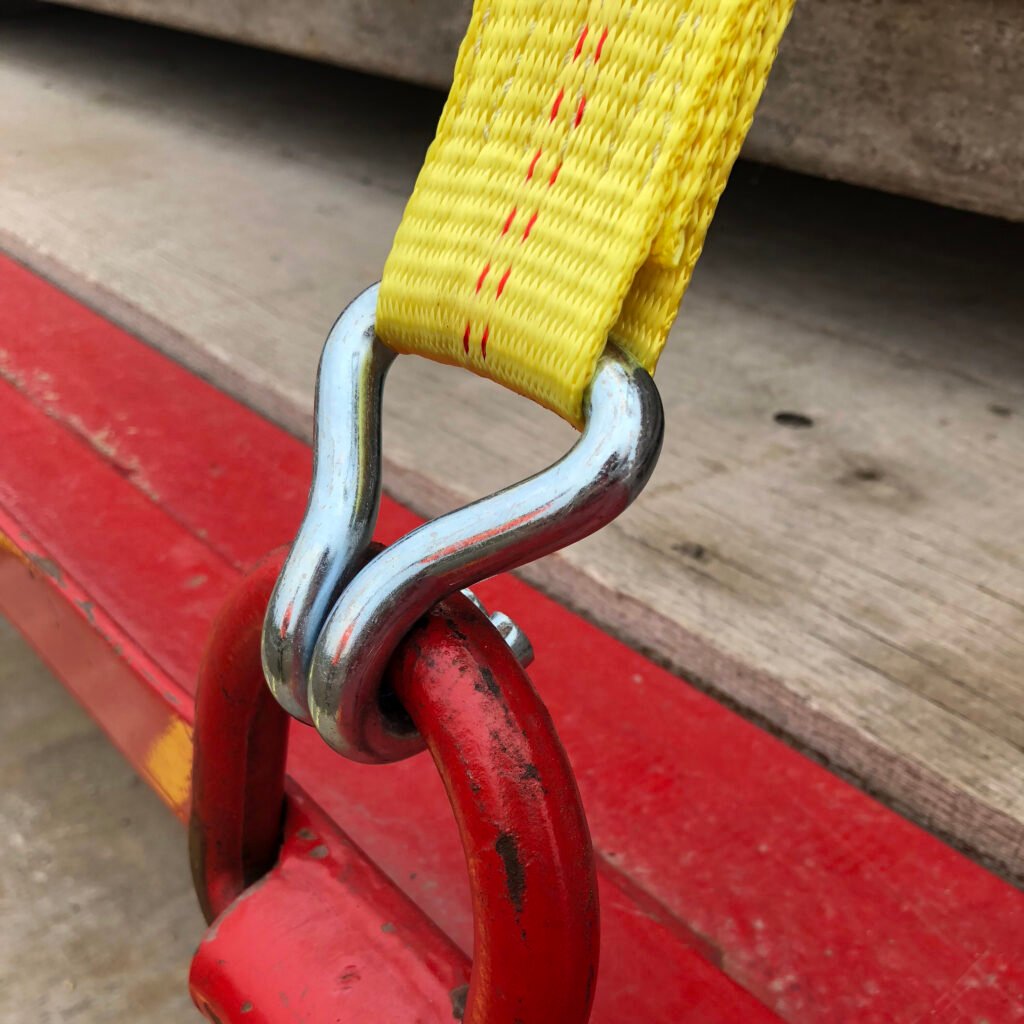 Metal L‑Track ring fitting connects heavy duty yellow tie‑down strap