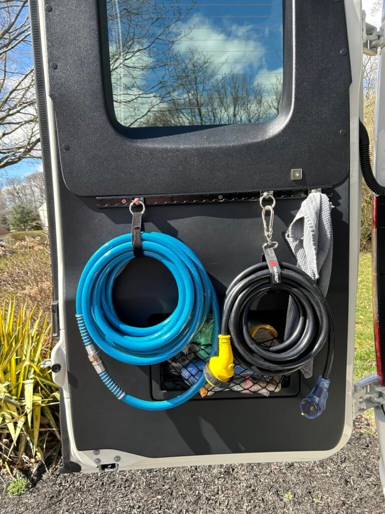 RV water and power utility connection port with blue hose, compatible with TORMAYS cargo securing hardware