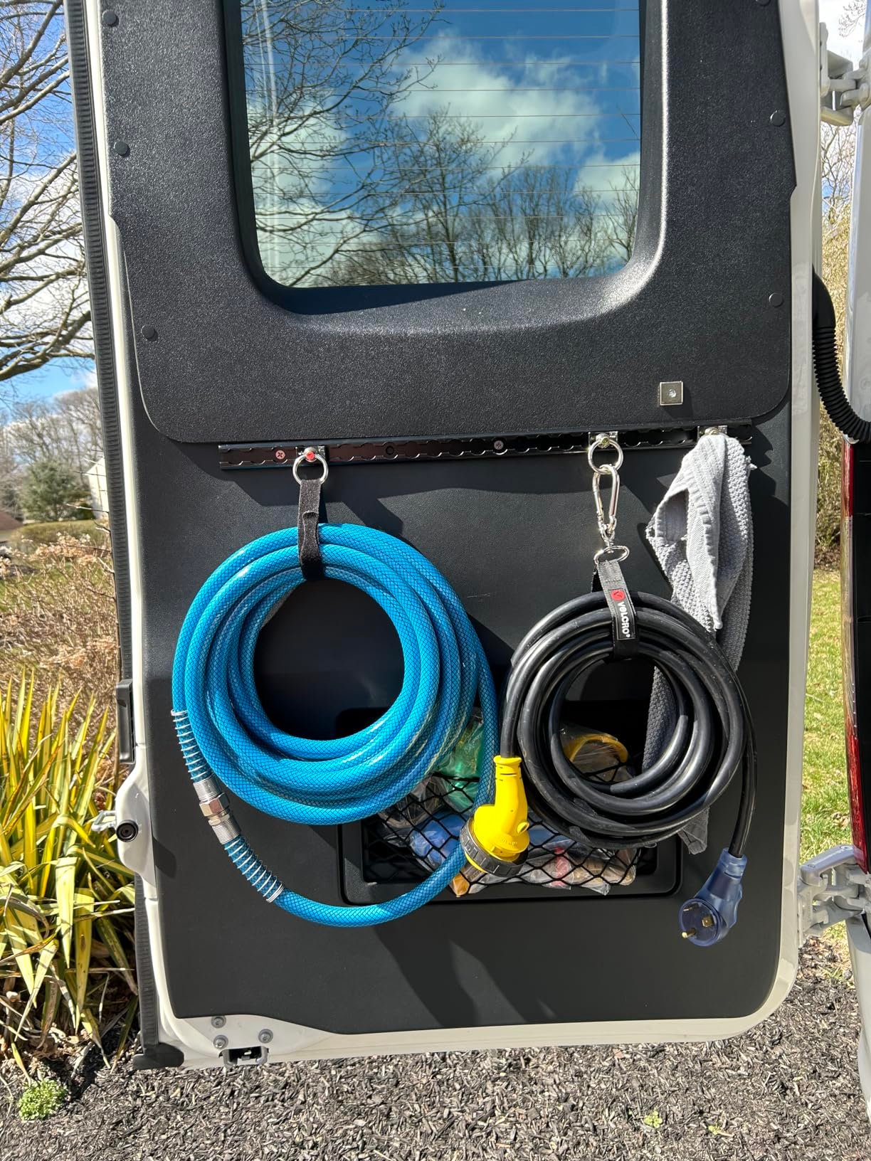 RV water and power utility connection port with blue hose, compatible with TORMAYS cargo securing hardware